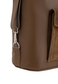 Borsa a spalla in pelle marrone con texture granulosa, dettaglio della tasca in suede e clip in metallo tono argento sulla tracolla.