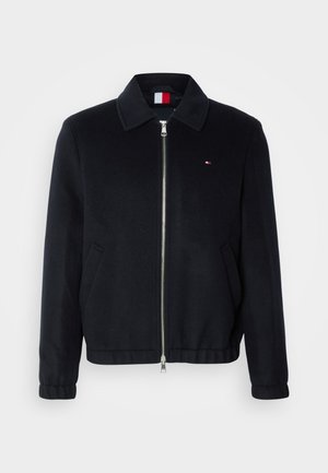 Black zip-up jacket with a collar, featuring side pockets, elastic cuffs, and a small logo patch. Smooth fabric texture.