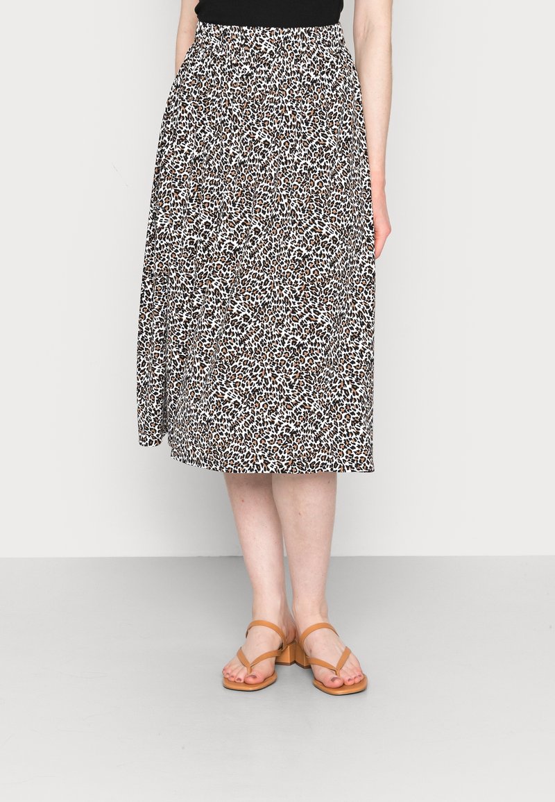 Jupe midi à motif léopard dans des tons blancs et marron, en tissu doux, avec une taille froncée et une coupe fluide, associée à des sandales beige.