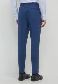 Blaue gemusterte Hose aus einem strukturierten Stoff, mit modernem Slim Fit, zwei Gesäßtaschen mit Knöpfen und schmal zulaufenden Beinen.