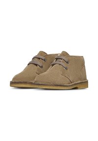 Brązowe zamszowe buty typu desert z okrągłymi noskami, dwoma otworami na sznurówki i szarymi sznurówkami. Teksturowana powierzchnia, miękki materiał i gumowe podeszwy.