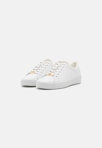 Weiße Ledersneaker mit einer strukturierten grauen Stoffzunge, dezenten goldenen Metallteilen an den Schnürsenkeln und einer flachen Gummisohle.