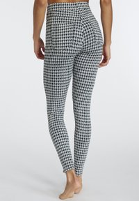 Bermude visokog struka u crno-bijelom houndstooth uzorku. Izrađene od rastezljivog materijala, imaju glatku teksturu i bez ukrasa.