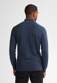 Pullover lavorato a maglia blu navy con un motivo testurizzato, maniche lunghe e colletto. Texture liscia con polsini e orlo a coste. Vista posteriore mostrata.