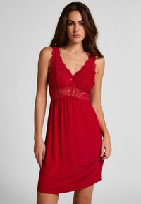 Czerwona nocna koszula z koronkowymi akcentami i regulowanymi ramiączkami, z dopasowanym koronkowym połowem i luźną, zwiewną spódnicą. Gładka tekstura materiału.