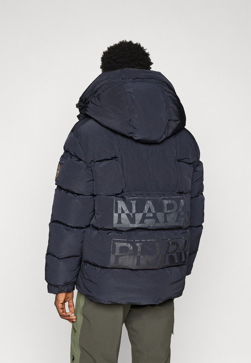 Doudoune bleu marine avec capuche, comportant des sections matelassées, des graphiques bien visibles "NAPA" et "PUR" au dos, et une finition texturée.