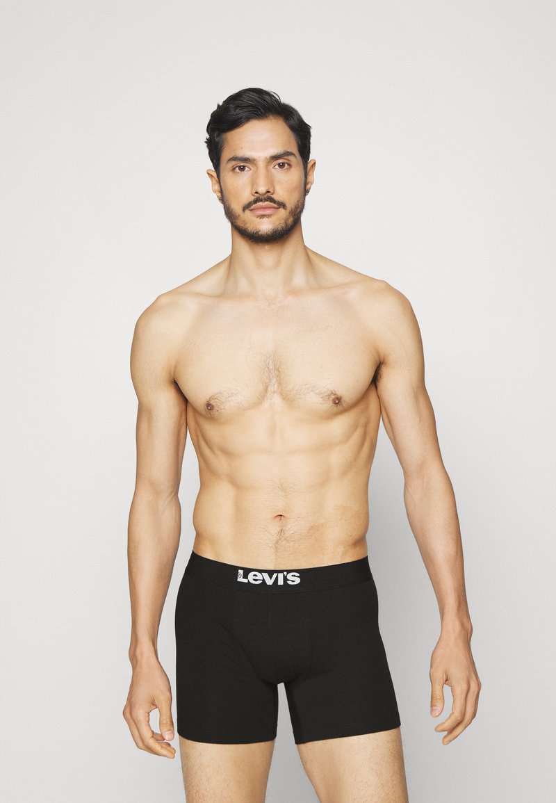 Svarte Levi's boxershorts med hvit logobånd, tilpasset design, glatt tekstur, modellen står mot en enkel lys bakgrunn.