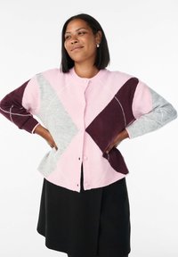 Pletená cardigan s geometrickým patchworkovým designem v růžové, burgundské a šedé barvě, s kulatým výstřihem a knoflíkovým zapínáním vpředu.