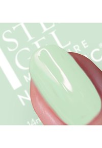 Smalto per unghie verde menta su un dito, finitura lucida, texture liscia, vista ravvicinata che mette in risalto forma e colore su uno sfondo morbido.