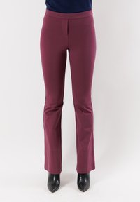 Pantaloni slim-fit bordeaux con texture liscia, orlo svasato e vita. Abbinati a stivali neri con punta a forbice e tacco alto.