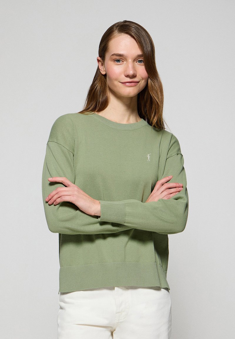 Ljusgrön stickad tröja med långa ärmar, ribbade muddar, avslappnad passform och en liten logotyp på bröstet. Minimalistisk design.
