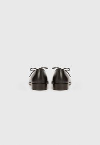 Μαύρα δερμάτινα παπούτσια με ομαλή υφή, στρογγυλεμένη μύτη και σχεδιασμό με κορδόνια. Διαθέτουν μικρά φιόγκους στο πίσω μέρος και χαμηλό, καφέ τακούνι.