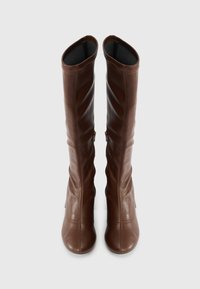 Brown leather knee-high boots with a smooth texture, slouchy design, and side zippers. Rounded toes and minimal stitching accents.