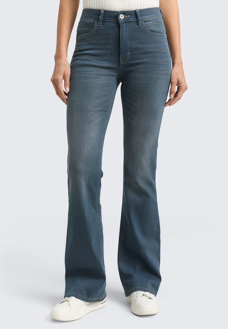 Blaue Jeans mit Glockenschnitt und mittelhoher Taille, vorderen Taschen und leichter Ausbleichung. Tragen Sie sie mit weißen Sneakers für einen lässigen Look.