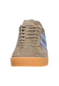 Sneaker in suede con tomaia marrone, righe blu e suola in gomma testurizzata. Linguetta leggermente imbottita e occhielli in metallo per i lacci.