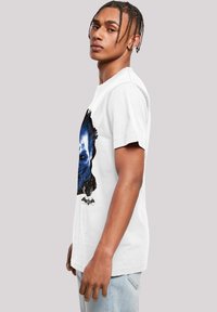 White cotton t-shirt featuring a prominent blue and black graphic print of a face, crew neckline, short sleeves, and relaxed fit.