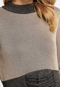 Maglione lavorato a maglia con colletto alto nero, corpo in taupe metallico e accenti neri testurizzati con dettagli a costine all'orlo.
