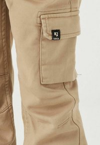 Hellebeige Cargo-Hosen verfügen über eine seitliche Tasche mit Klappe, die mit einem kleinen schwarzen "GARCI(A)"-Logo gekennzeichnet ist, sowie sichtbare Nähte.