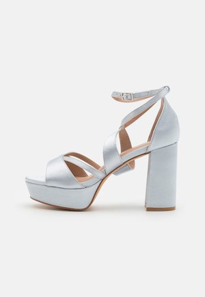 Silberne Satin-Plattformsandalen mit einem dicken Blockabsatz, offenen Zehen und Überkreuz-Riemen am Knöchel. Mit einer Schnallenverschluss für einen sicheren Sitz.
