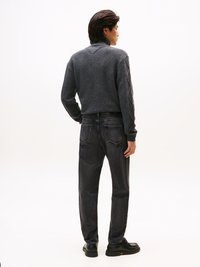 Pull en tricot gris à col montant, associé à un jean en denim foncé. Caractéristiques : motif texturé et chaussures noires.
