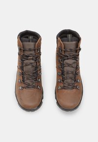 Barna bőr túracipők fekete textil béleléssel, kontrasztos narancssárga varrással és fémből készült cipőfűző hardverekkel, masszív gumitalppal.