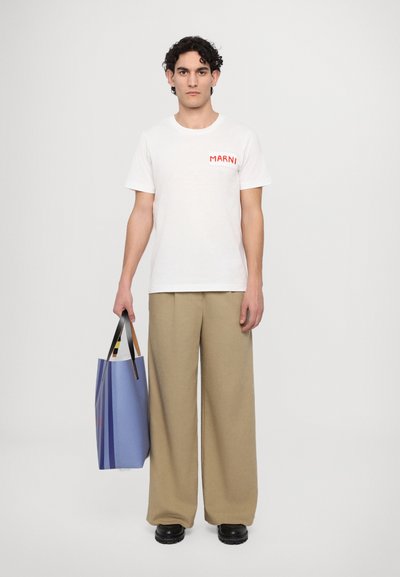 Tricou alb din bumbac cu logo roșu "MARNI", pantaloni largi bej, și o geantă de umăr căptușită, albă cu dungi albastre și mânere negre. Încălțăminte neagră.