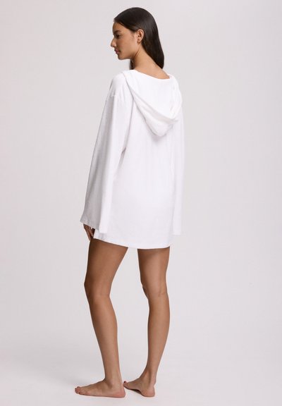 Λευκή τουνίκ από περκάλι με κουκούλα, μακριά μανίκια, άνετη γραμμή, μήκος μέχρι τα μέσα μηρών, με πλαϊνές σχισμές και απαλή υφή.