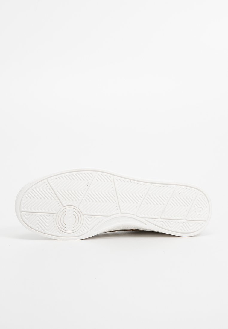 Podeszwa białego buta casualowego z wzorzystą bieżnią i okrągłym logo blisko pięty na jednolitym białym tle.