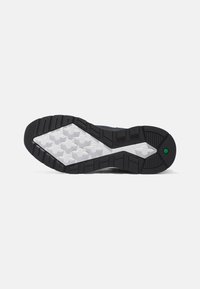 Suela de zapatilla deportiva con un dibujo de goma negro, patrones de tracción blancos y un acento verde cerca del talón. Texturizado para un mejor agarre.