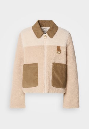 Műszőrme dzseki krémszínű testtel, barna kordbársony gallérral és két felvarrt zsebbel. Elöl cipzárral és fém kiegészítővel rendelkezik.