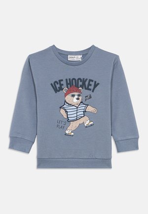 Blå barnegenser med lange ermer, med en bjørn som har på solbriller, rød hatt og skøyter, og teksten "ICE HOCKEY" og "LET'S PLAY."