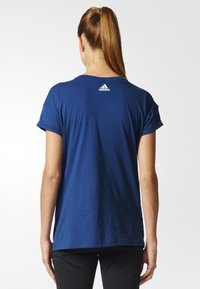 Mörkblå bomullströja med korta uppvikta ärmar, rundad hals och liten vit Adidas-logga på övre ryggen. Mjuk textur, avslappnad passform.