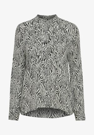 Fekete-fehér zebramintás blúz hosszú ujjakkal, magas nyakkivágással és laza szabással, pleated részletekkel és ívelt alsó résszel.