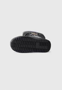 Suela de bota de goma negra con un patrón de taco texturizado, base plana y acentos moldeados, diseñada para ofrecer tracción y durabilidad.