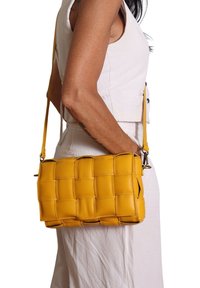 Borsa a tracolla in pelle intrecciata gialla con forma rettangolare, dotata di una tracolla rimovibile e una texture liscia.