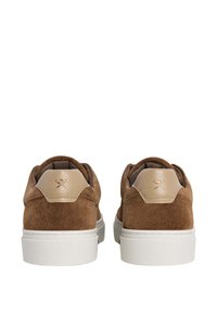 Sneakers in suede marrone con una linguetta in pelle tan, suola in gomma bianca e logo discreto sul retro. Texture morbida e design arrotondato.