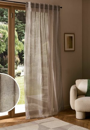 Transparenter beiger Vorhang, der an einer schwarzen Stange in einem Wohnzimmer mit Holzboden und beigem Sofa nahe einer Glastür hängt.