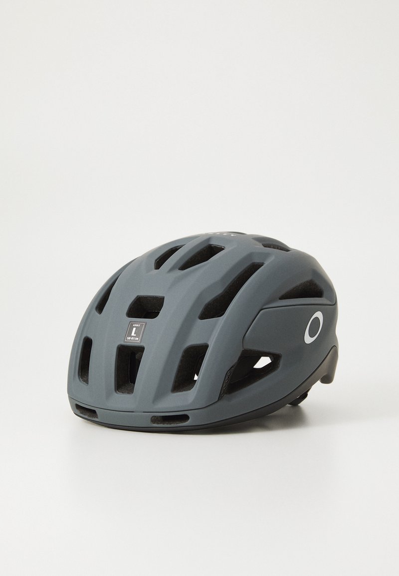 Grauer Fahrradhelm mit matter Oberfläche, mehreren Belüftungsöffnungen und einem reflektierenden Logo. Verstellmechanismus auf der Rückseite für den perfekten Sitz.
