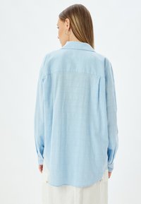Lichtblauw overhemd met lange mouwen en een relaxed fit, een puntige kraag, knoopmanchetten en een gestructureerde stof. Licht gebogen zoom.