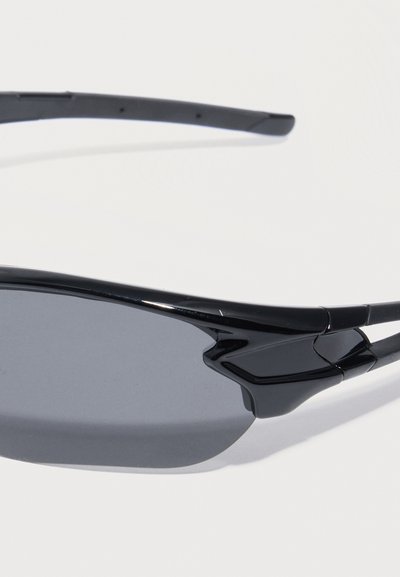 Αθλητικά μαύρα γυαλιά ηλίου τύπου wraparound με σκοτεινούς φακούς και λεπτούς βραχίονες σε λευκό φόντο.