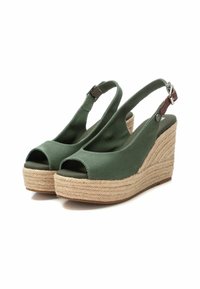 Sandalias de cuña de tela verde con diseño de puntera abierta y tirante trasero. Presentan una suela de yute trenzado y un acento de tira con hebilla de metal.