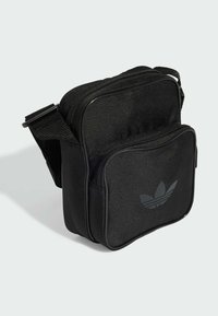Borsa a spalla nera con zip realizzata in tessuto testurizzato. Presenta una tasca frontale e un logo in rilievo sul davanti. Inclusa una tracolla regolabile.