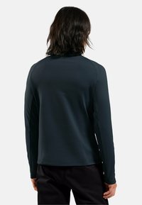 Langärmliges gemustertes schwarzes Performance-Shirt mit glatter Textur, enganliegendem Design und hohem Kragen, ausgestattet mit Raglanärmeln für mehr Bewegungsfreiheit.