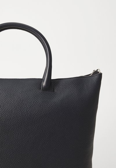 Geantă tote din piele neagră cu textură pebble, mânere rotunjite și închidere cu fermoar. Prezintă o formă structurată, un design minimal și fără hardware vizibil.
