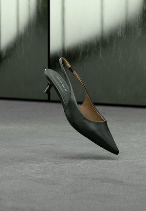 Μαύρο γυναικείο παπούτσι με ακρυβολέκτη μύτη και λεπτό λουράκι τύπου slingback, με τακούνι kitten και ετικέτα "ANNA FIELD" στην εσωτερική σόλα, σε θολό γκρι φόντο.