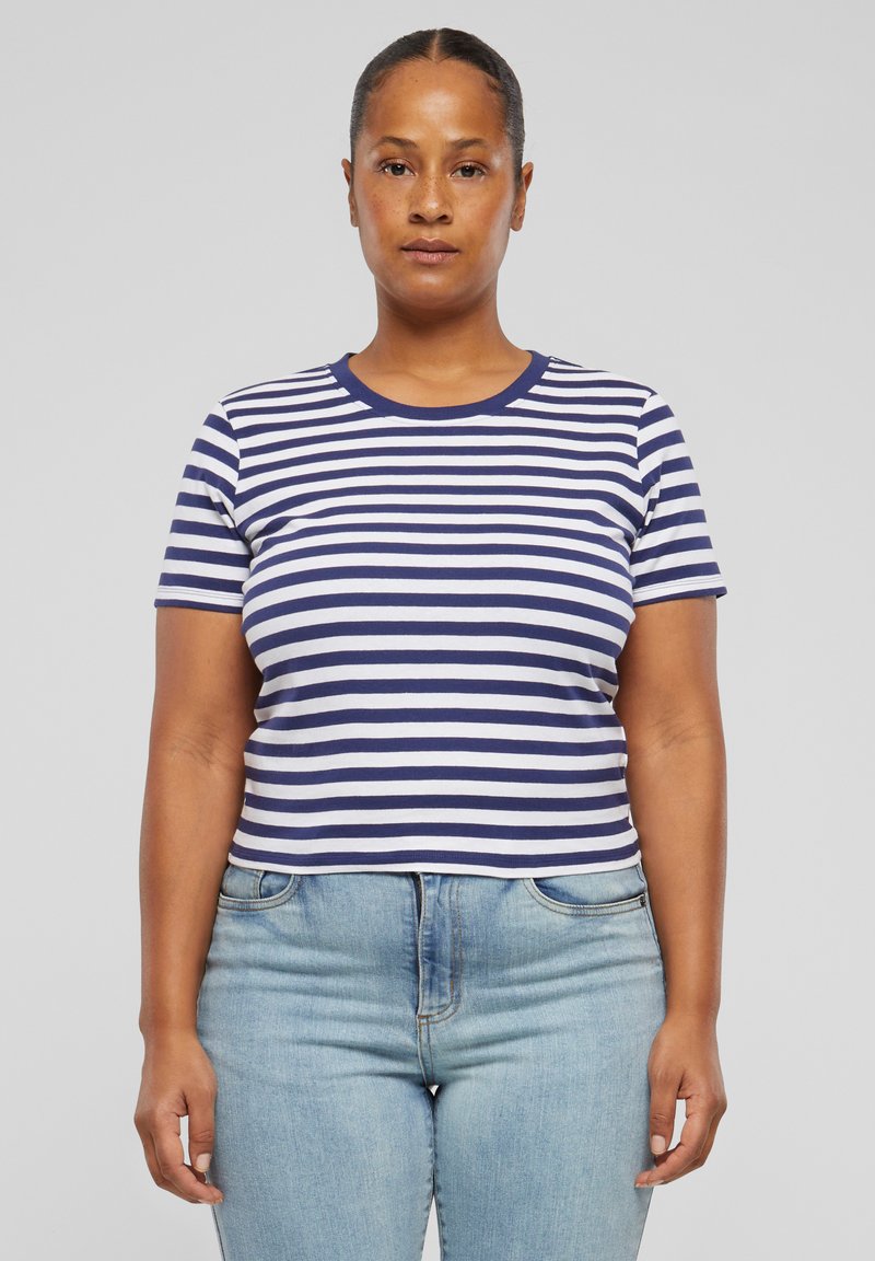 Camiseta de rayas con mangas cortas, con rayas horizontales blancas y azul marino. Cuello redondo y diseño ajustado. Combinada con jeans de color azul claro.