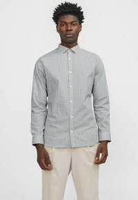 Camicia a maniche lunghe con bottoni, caratterizzata da un motivo geometrico in blu e bianco, realizzata in tessuto leggero con colletto standard.