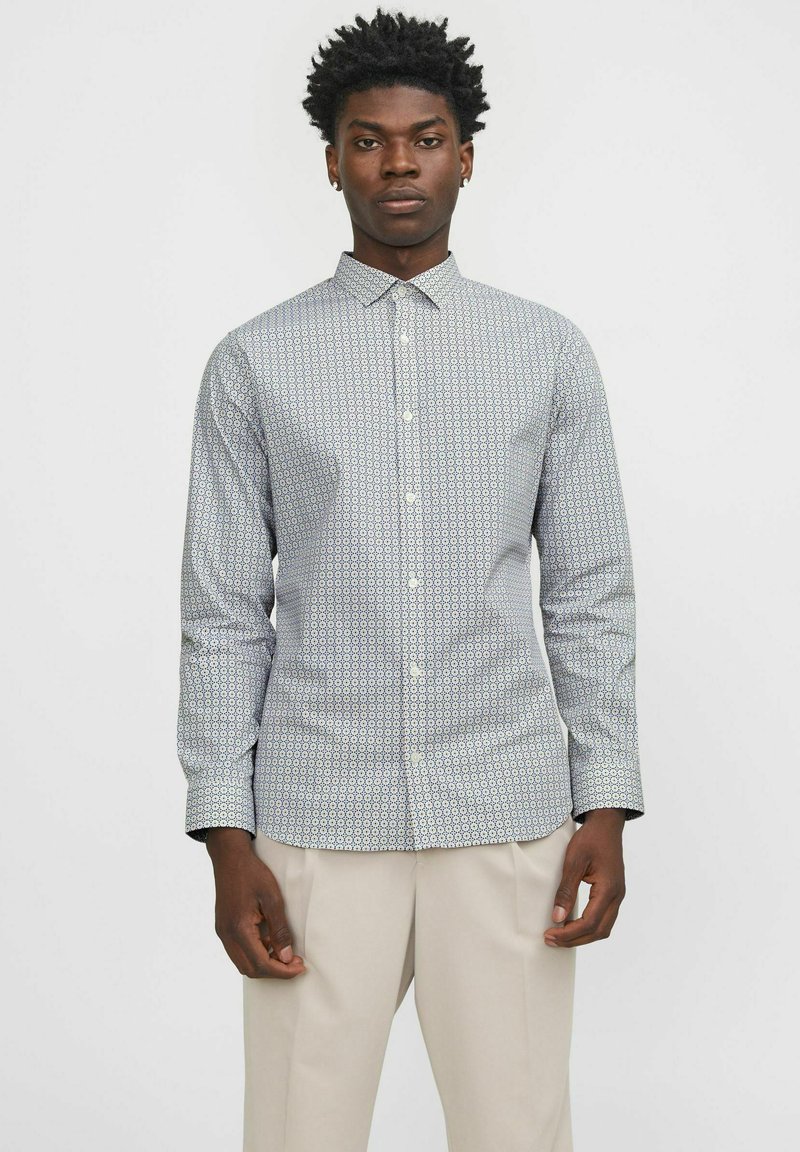 Camicia a maniche lunghe con bottoni, caratterizzata da un motivo geometrico in blu e bianco, realizzata in tessuto leggero con colletto standard.