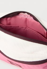 Ανοικτό ροζ και λευκό πορτοφόλι με φερμουάρ που δείχνει καθαρές εσωτερικές επιφάνειες με επιπλέον μικρότερη θήκη στο εσωτερικό.