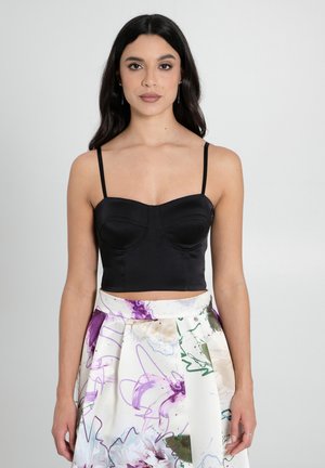 Schwarzes Satin-Crop-Top mit strukturiertem Bustier und dünnen Trägern, kombiniert mit einem Rock im Blumenmuster mit lila und grünen Akzenten.